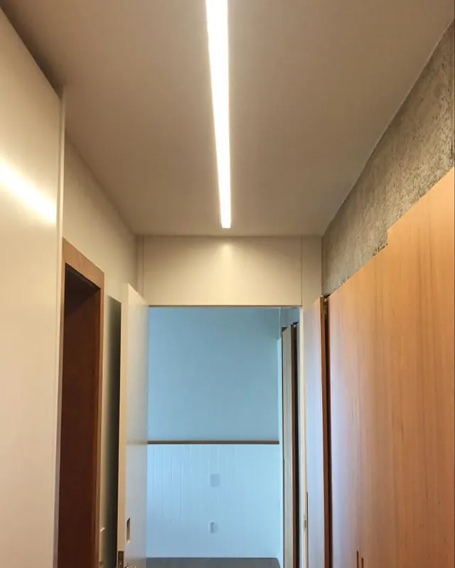 Corredor com luz em linha no forro e portas de madeira