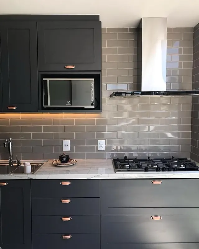 Cozinha com armários planejados em grafite, bancada em pedra, cooktop e coifa