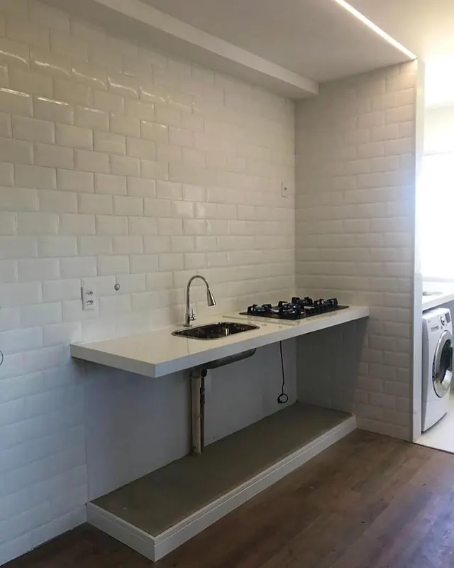 Cozinha compacta com revestimento metrô branco e bancada em pedra