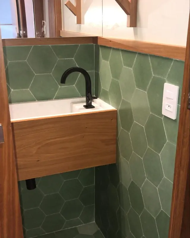 Lavabo com revestimento hexagonal verde, cuba em madeira e torneira preta