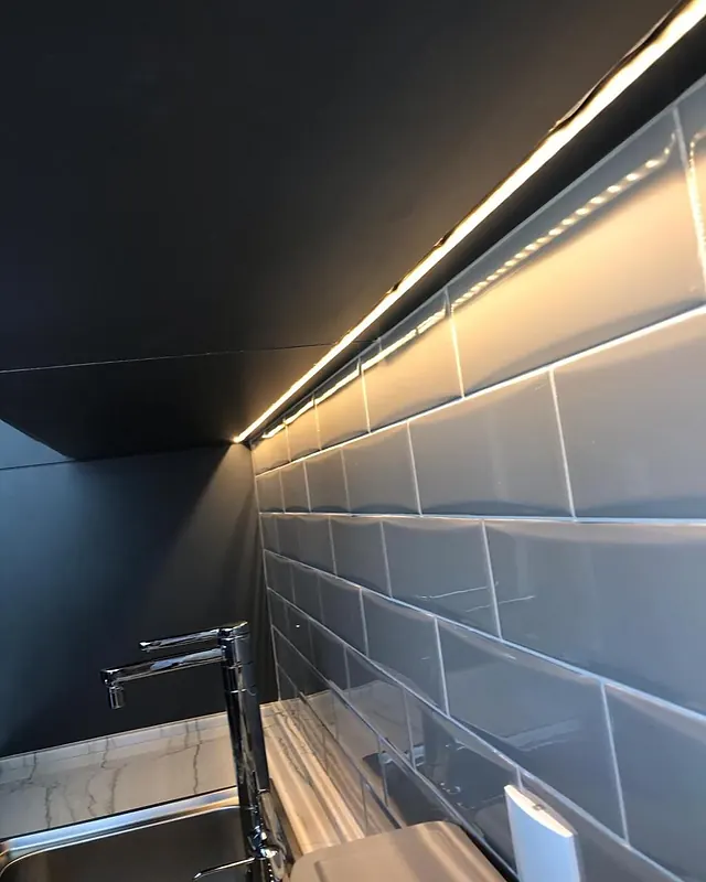Parede com revestimento metrô e iluminação em linha sob o armário