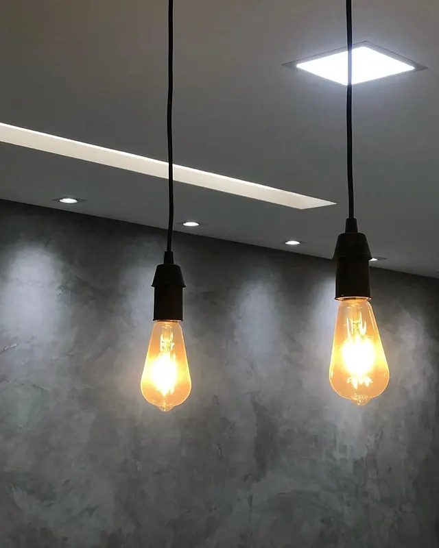 Pendentes com lâmpadas de filamento sobre parede em cimento queimado