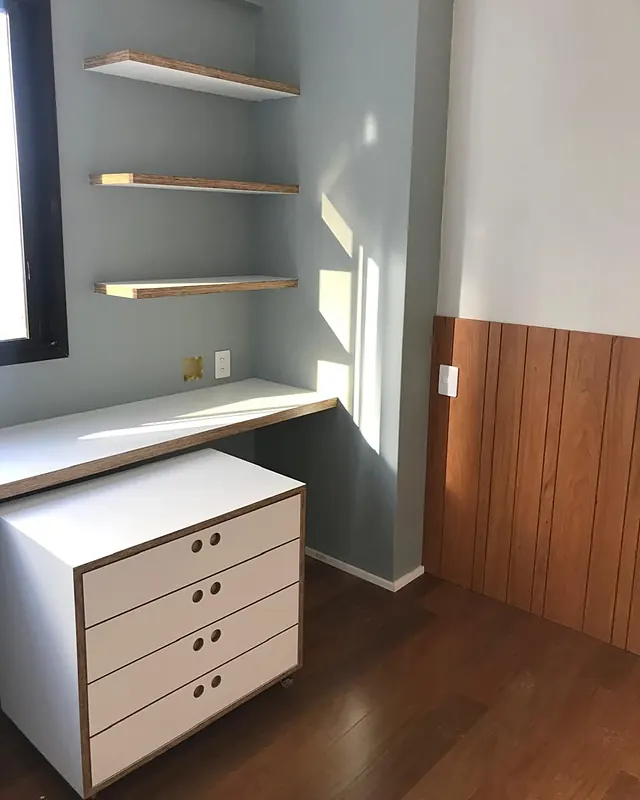 Quarto com bancada de estudo, gaveteiro branco e painel de madeira