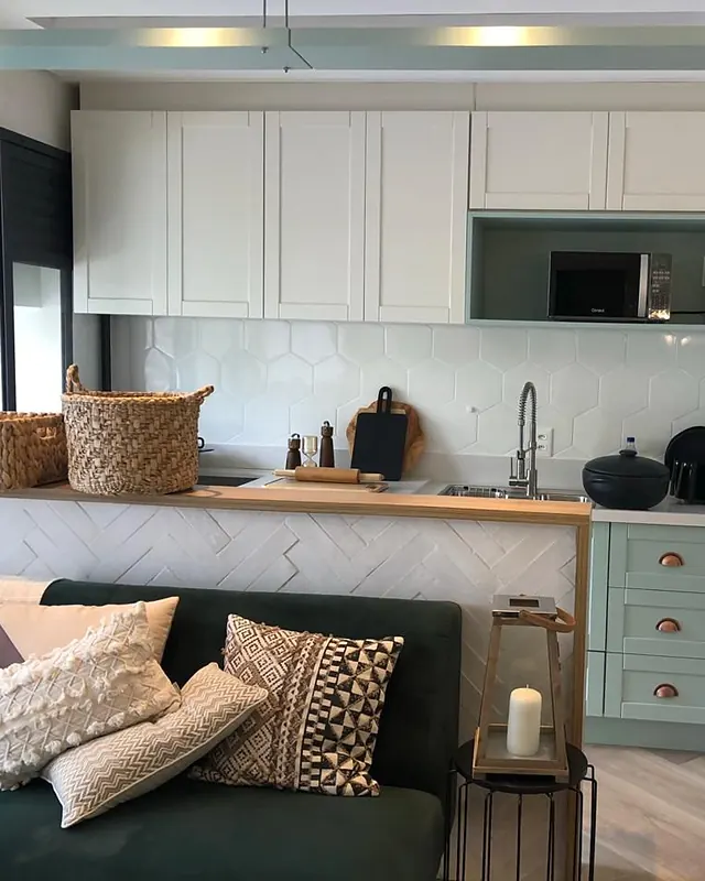 Sala ampla com sofá integrada à cozinha planejada com armários claros